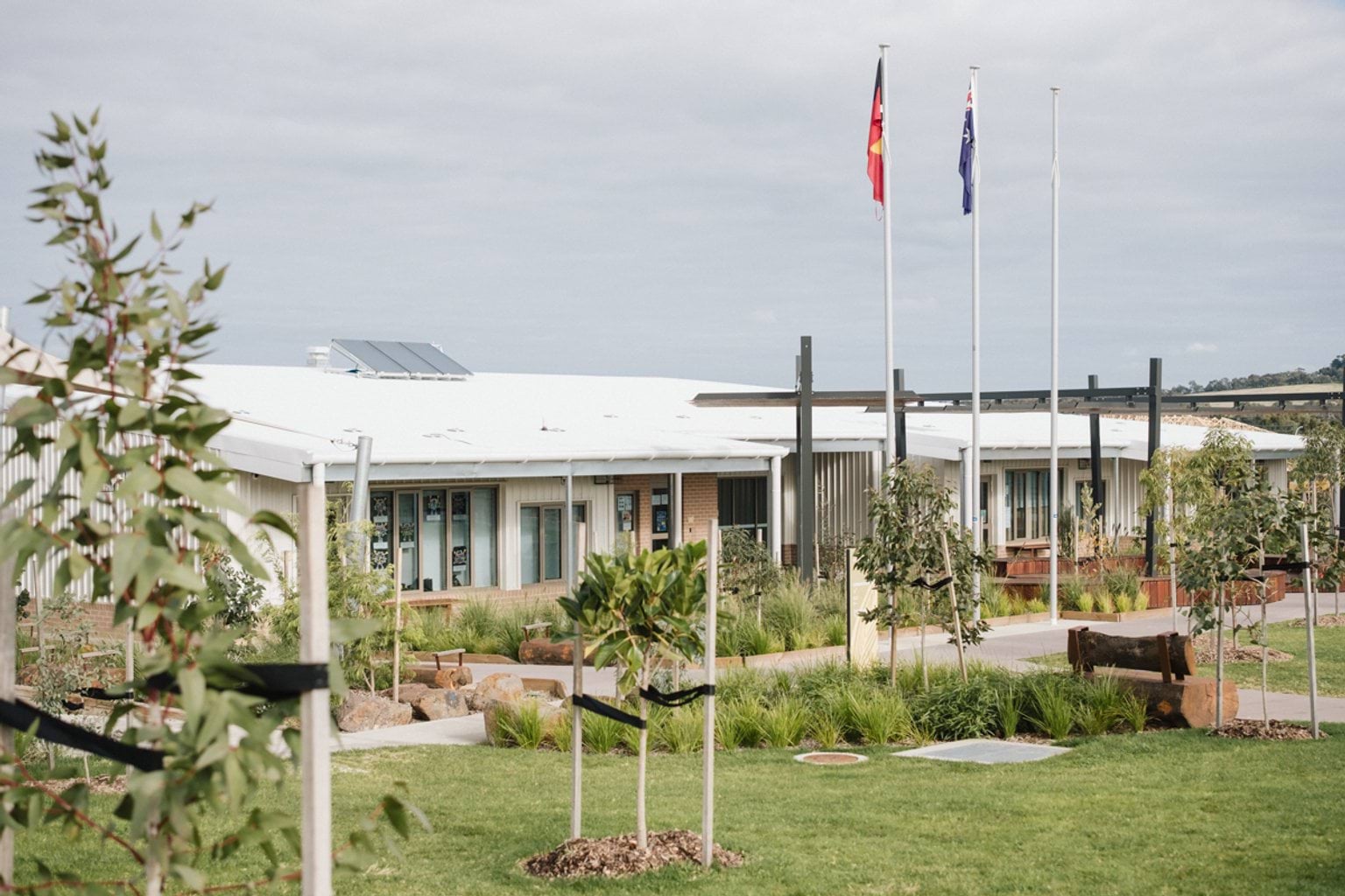 Outdoor green space and garden with flagpoles and school building in background
