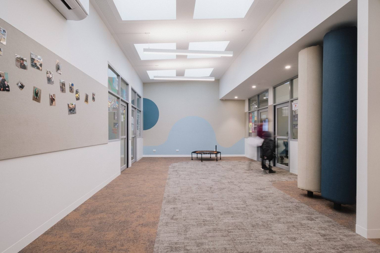 Breakout area with soft poles, felt pin board along the walls and grey and brown carpet