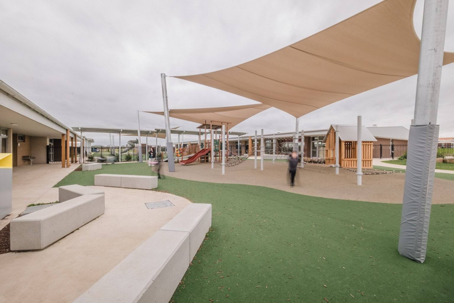 Outdoor covered play area with astro-turf, bench seats, and a playground