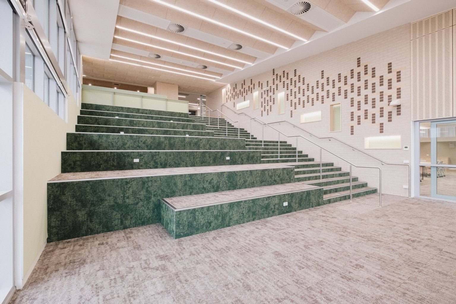 Auditorium area with a stairwell and green staggered landings leading down to carpeted area