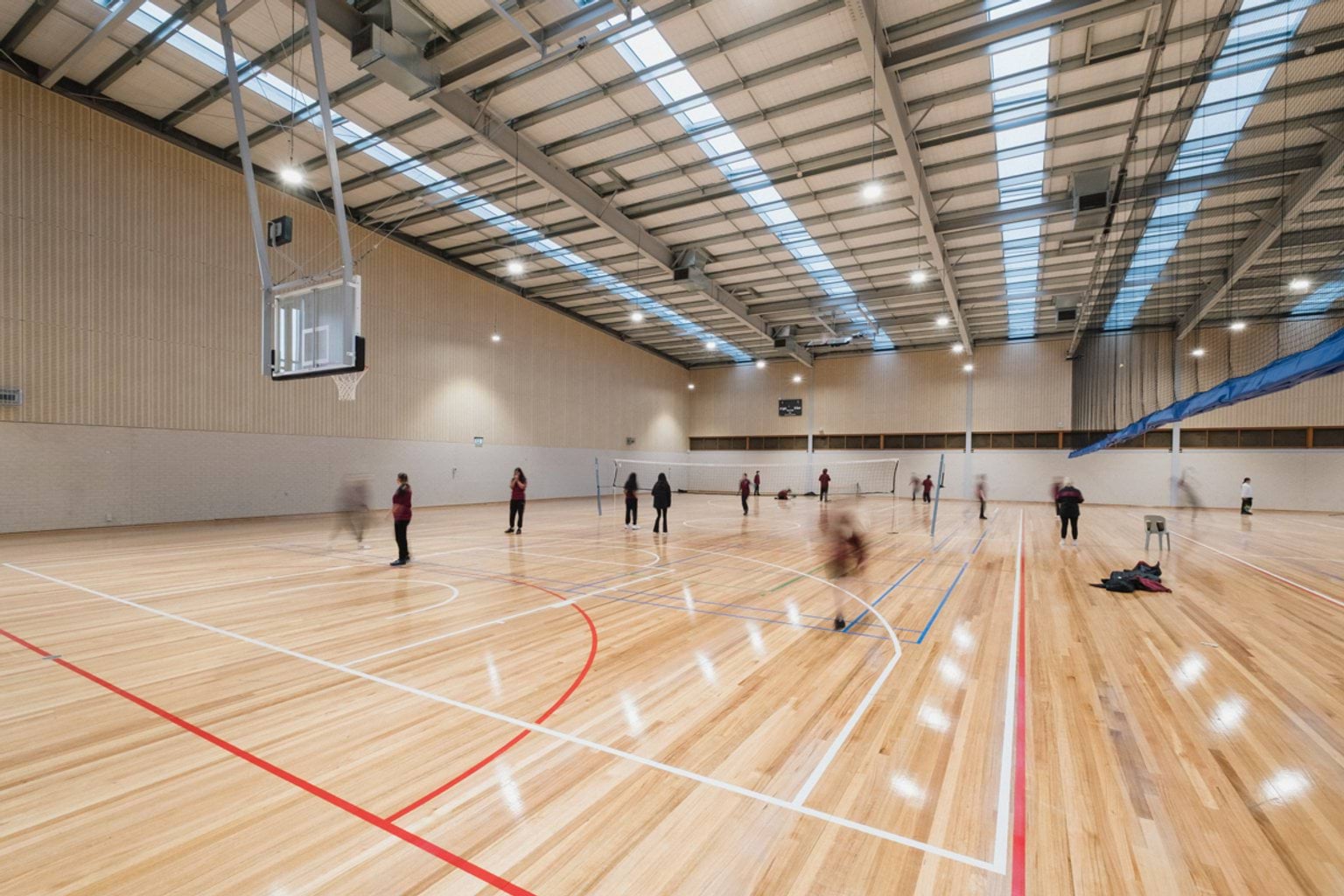 Basketball stadium with two courts and blurred students spread across the courts