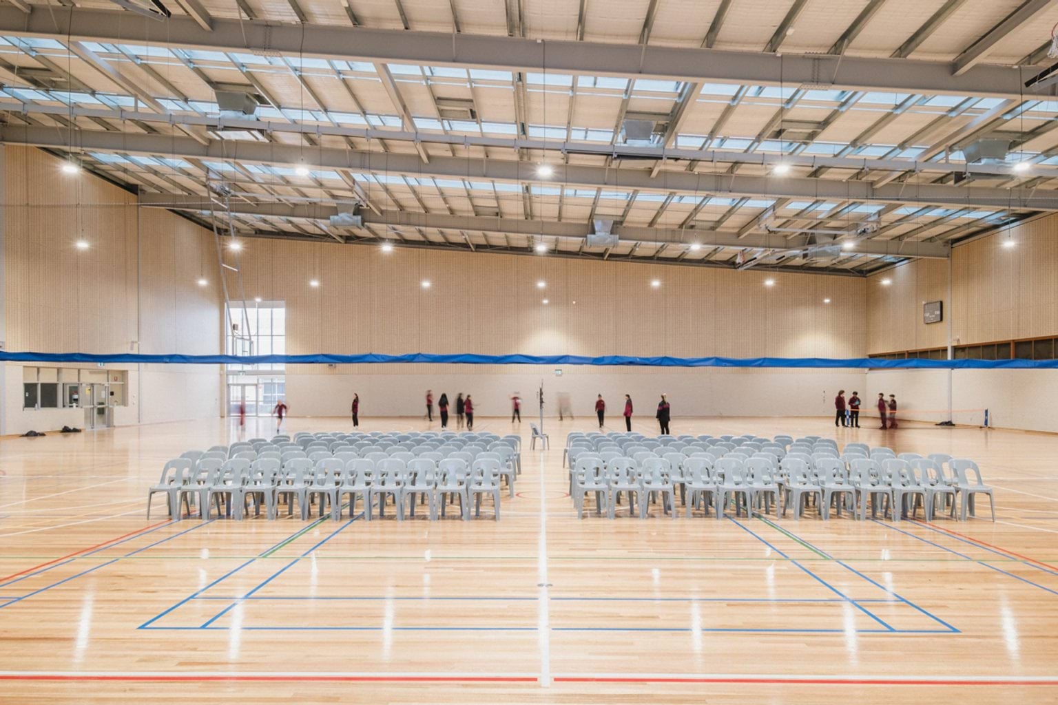 Basketball stadium with two sets of rows of chairs and blurred students on the far court