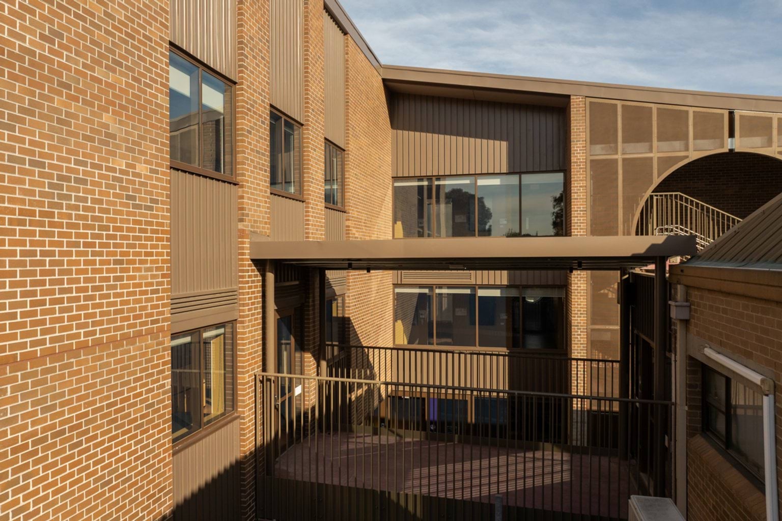 Brown brick buildings connected by brown metal sheltered walkway