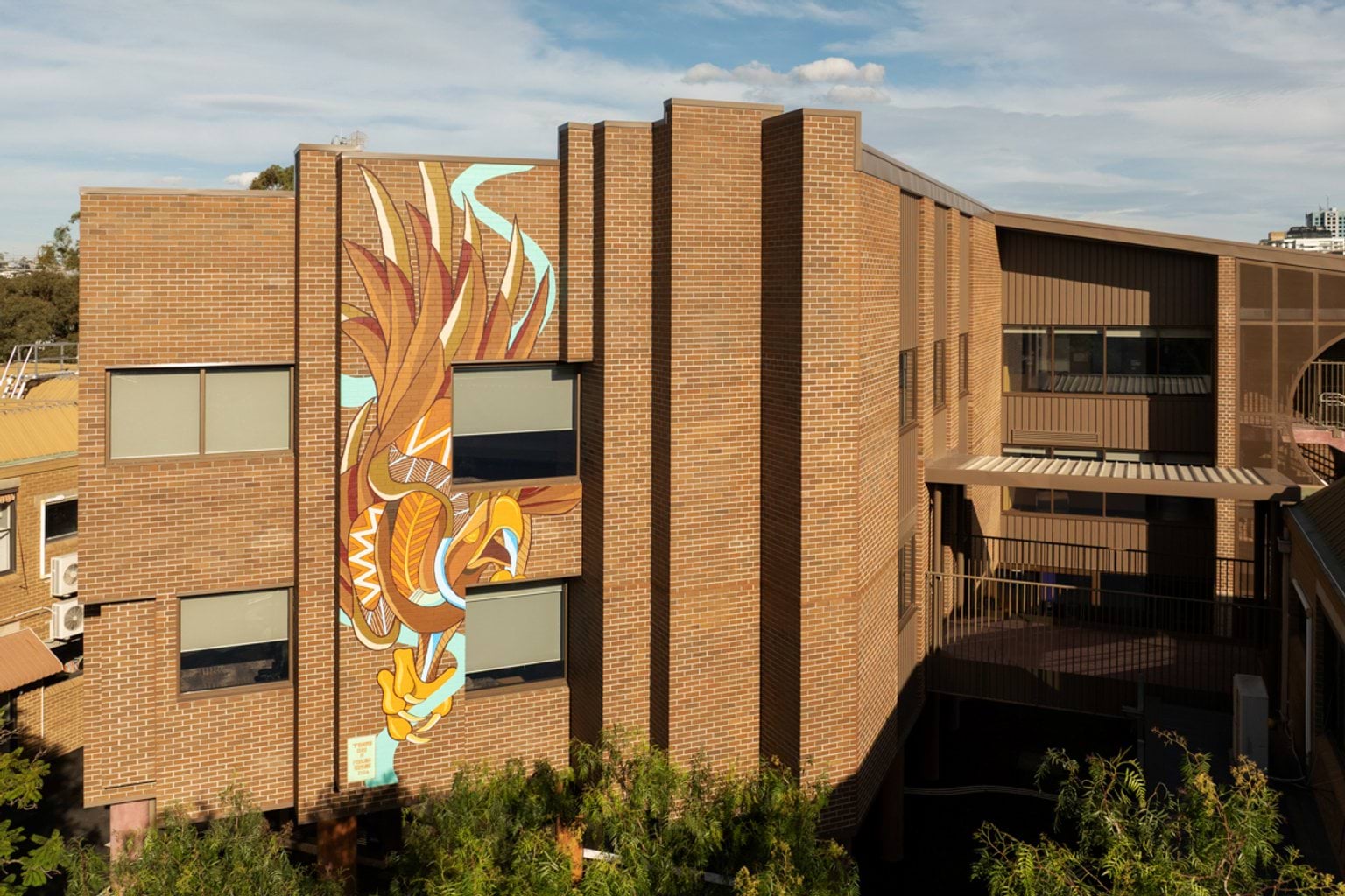 Brown brick buildings with indigenous artwork of Bunjil on the wall