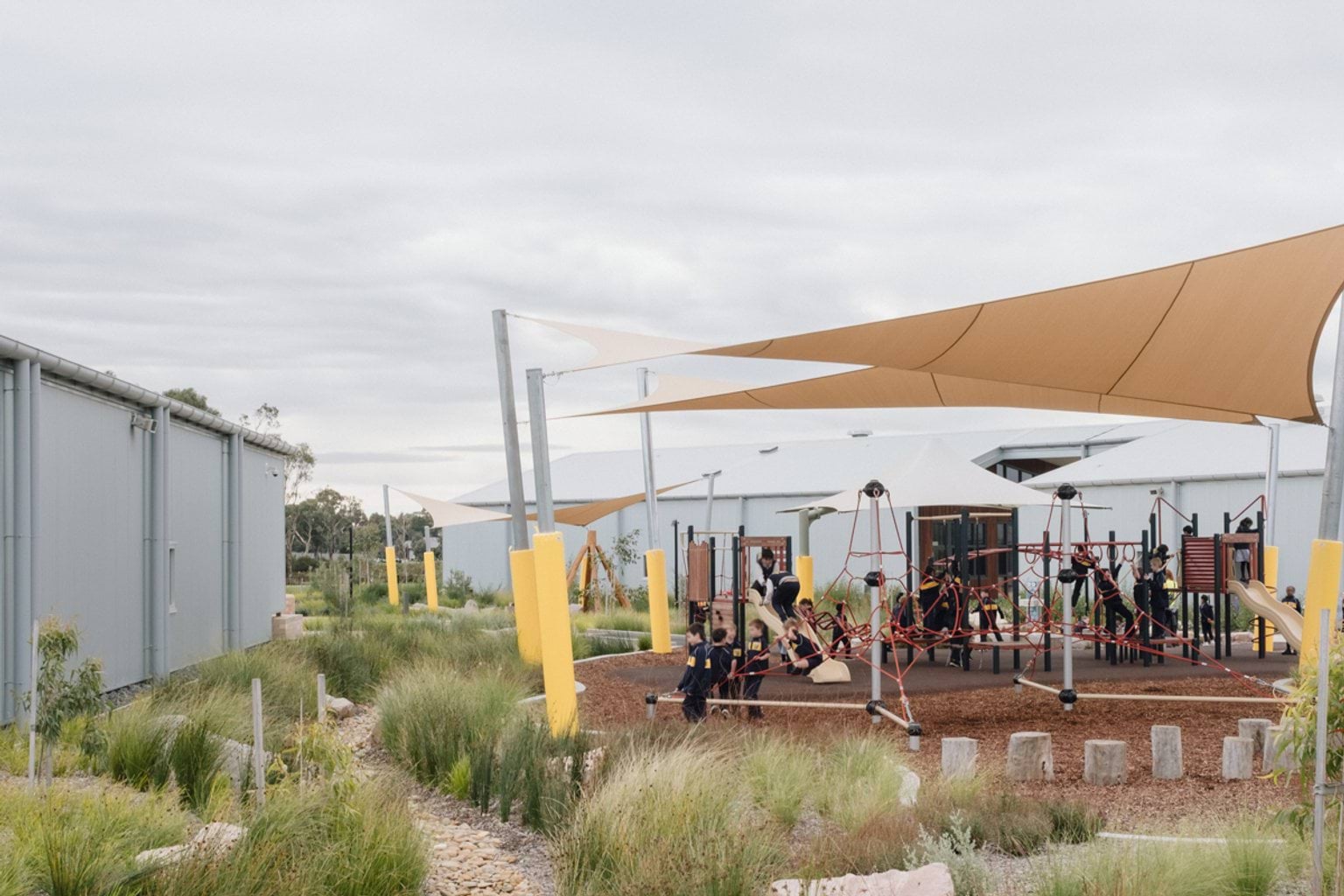 Covered playground area with garden beds in the foreground
