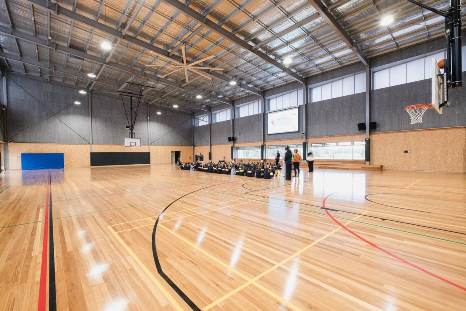 Indoor basketball stadium. We can see students seated on the far side of the court