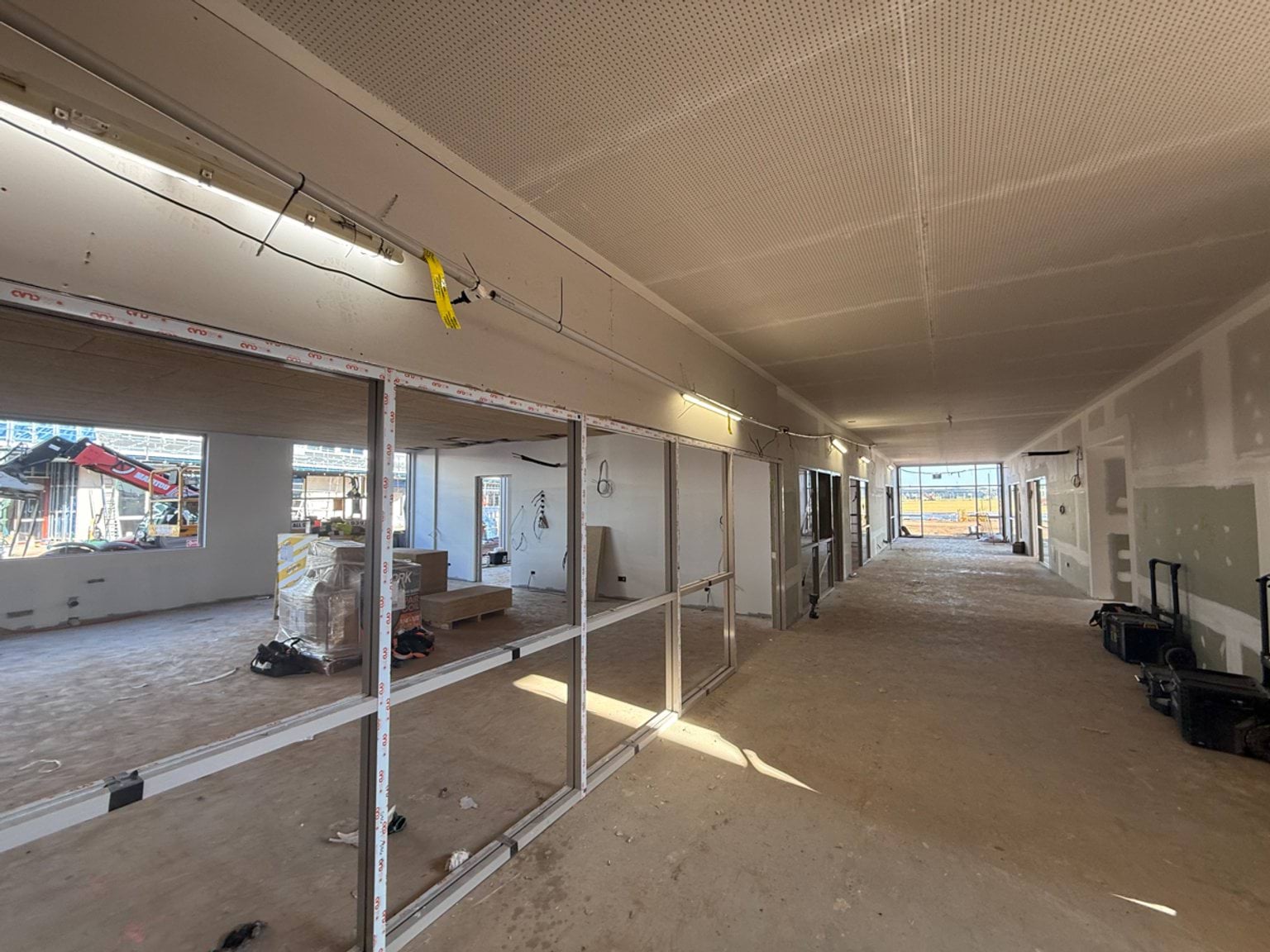 Classroom and hallway under construction with plaster walls and window frames