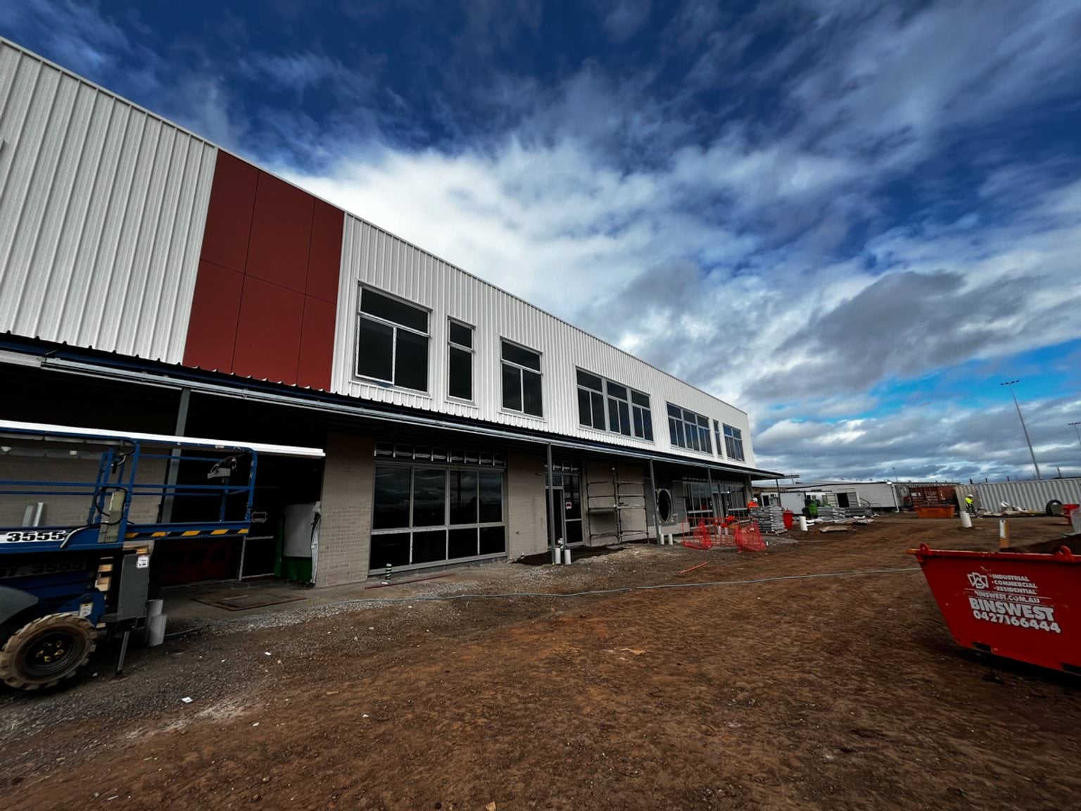 Two-storey building with dirt ground and construction equipment visible