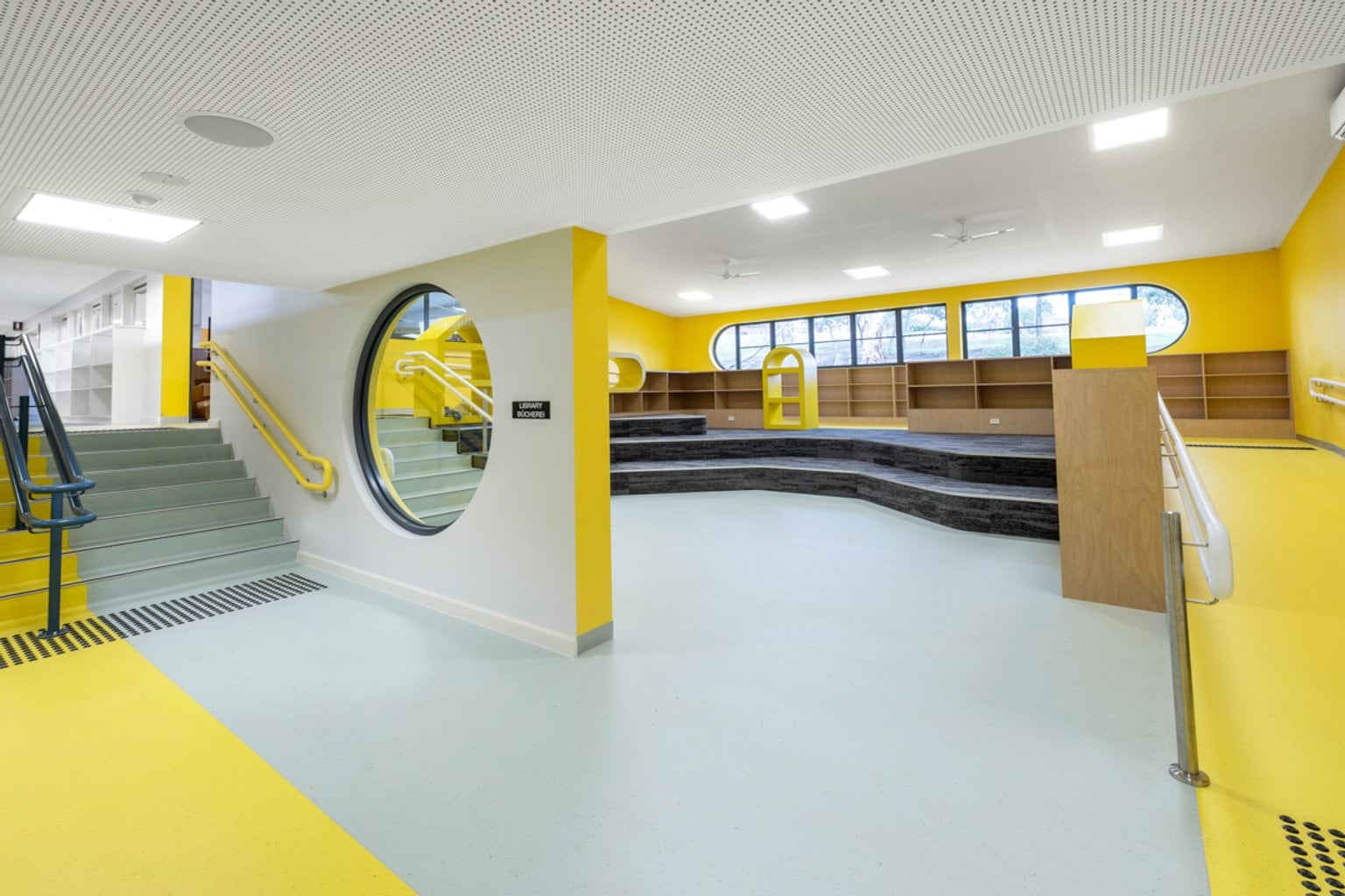 An open-plan learning area with yellow painted feature walls and pathways. 