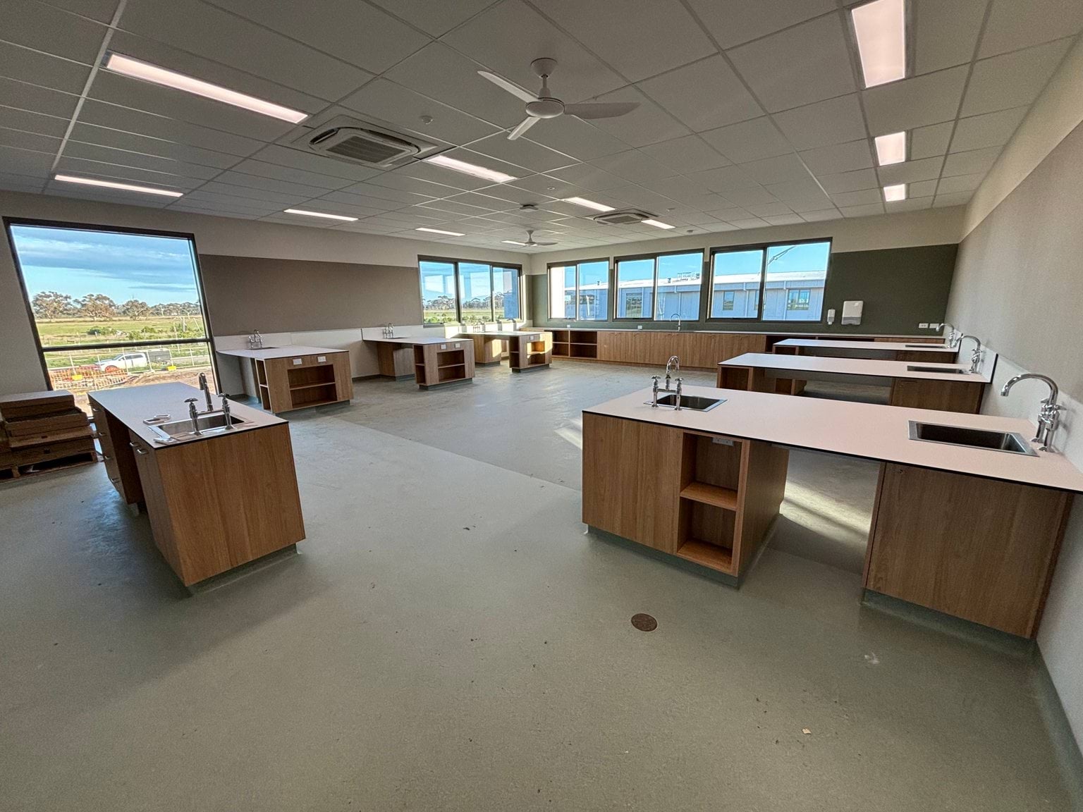 A classroom under construction with newly fitted benchtops and sinks throughout