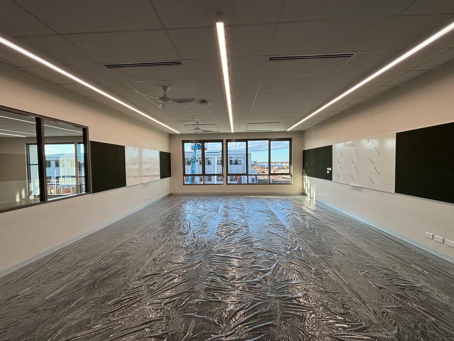 A classroom space with strip lights, whiteboard and newly fitted flooring