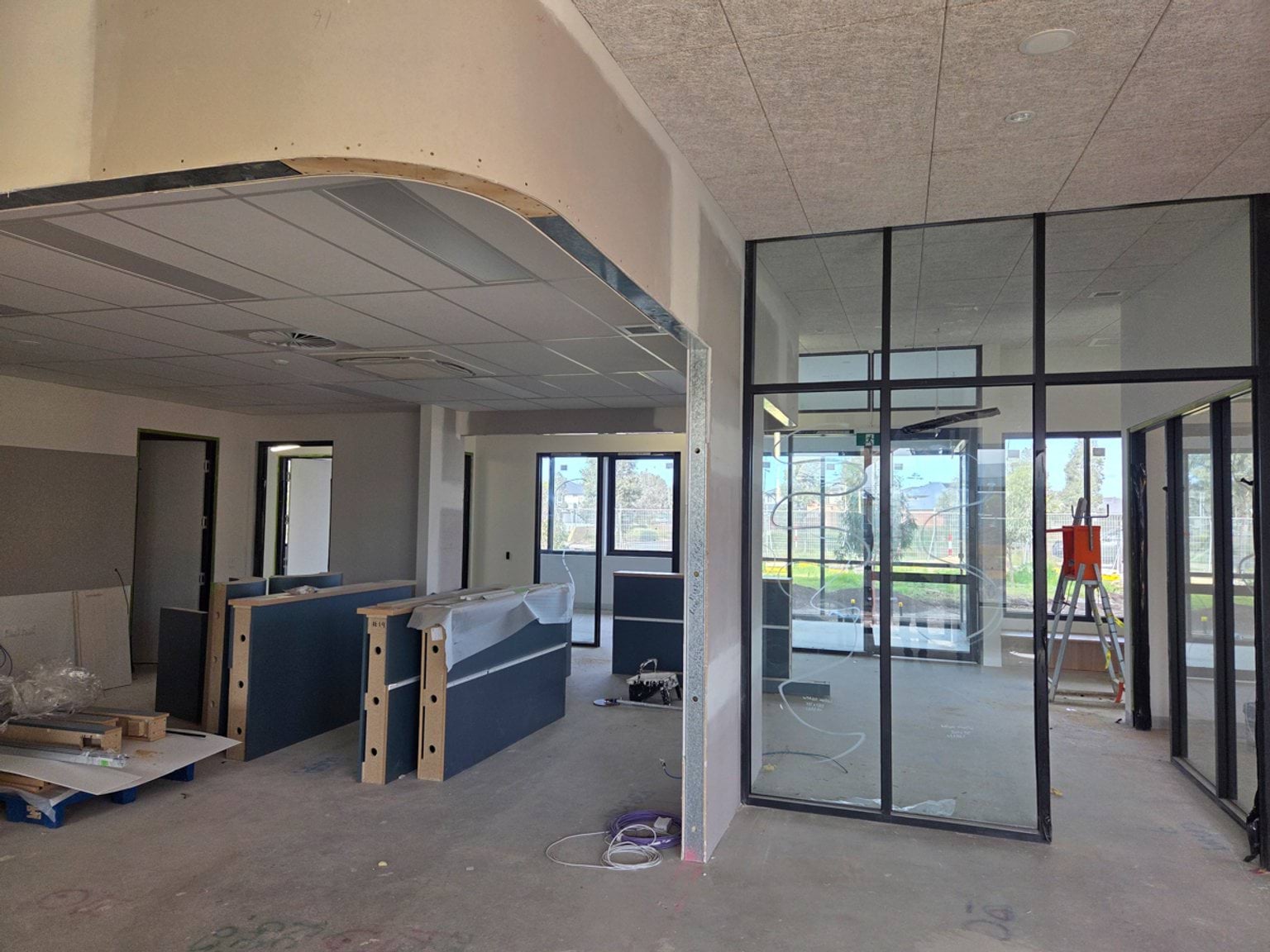 An indoor space under construction, with unfinished walls, exposed ceilings and bare concrete floors.