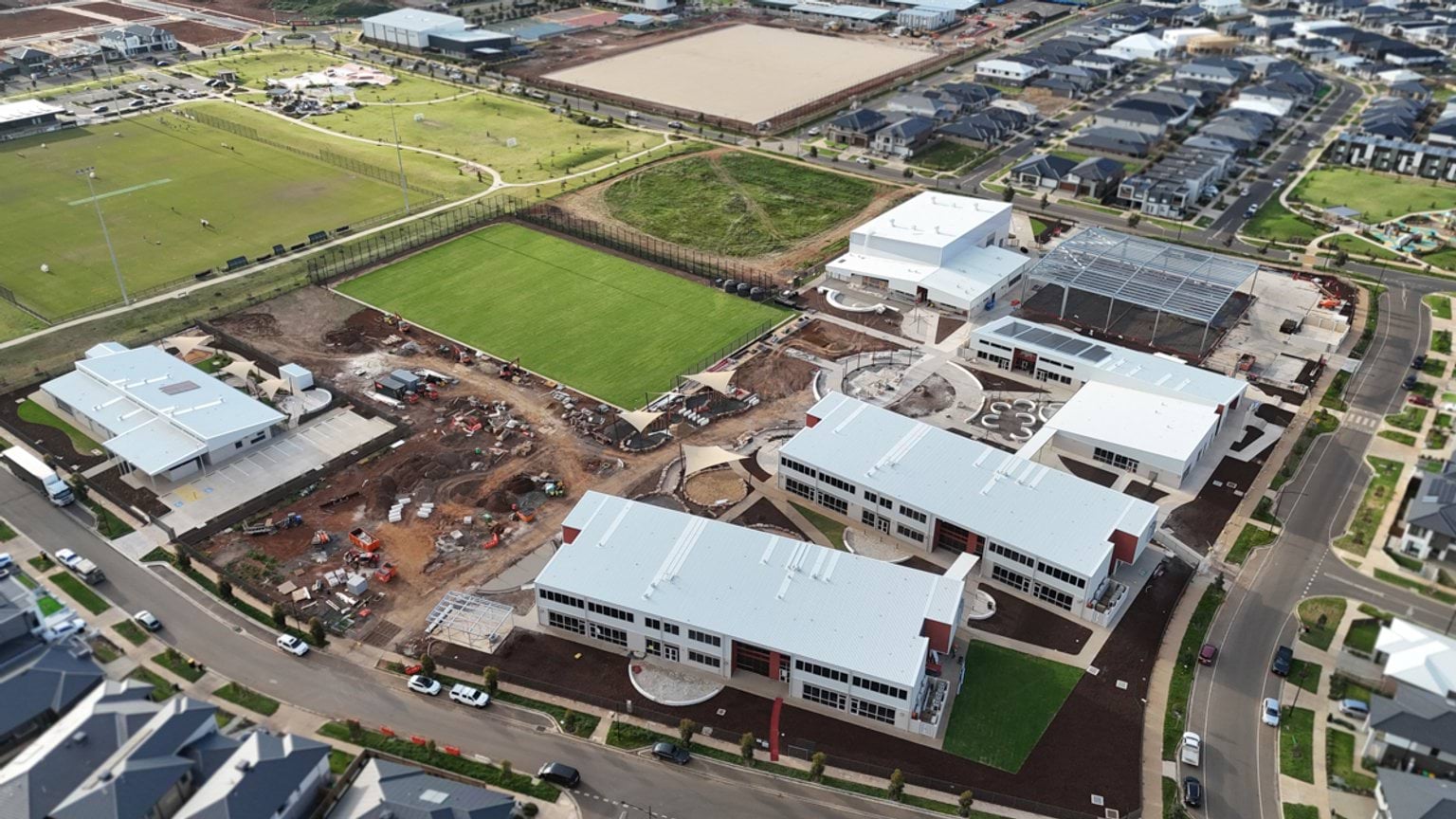 Aerial view of a kindergarten near completion, showing several new buildings, landscaped areas, roads and surrounding residential homes.