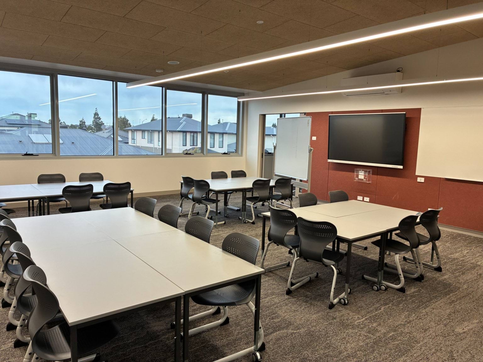 A modern classroom with flexible seating, large windows and digital teaching screens.